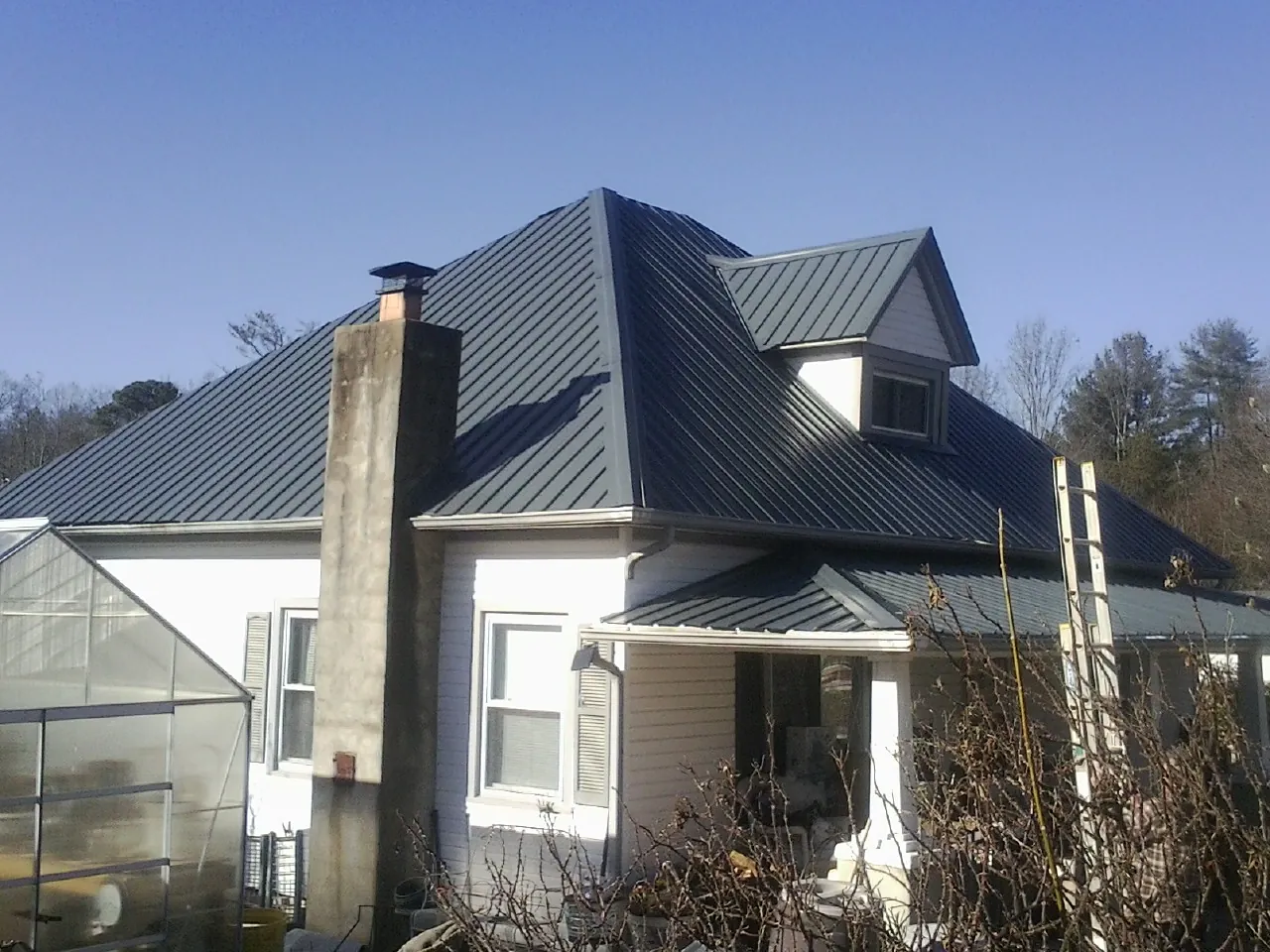 Dark blue standing seam metal roof on a white farmhouse with dormer — Slate & Tile Roof Repair by Roofing Brothers in Hershey