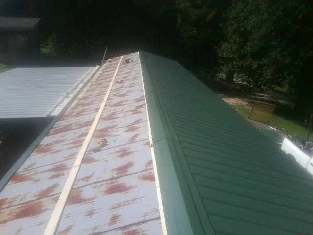 Old rusted panels beside newly installed green metal roofing — Wind Damage Roof Repair by Roofing Brothers in Hershey