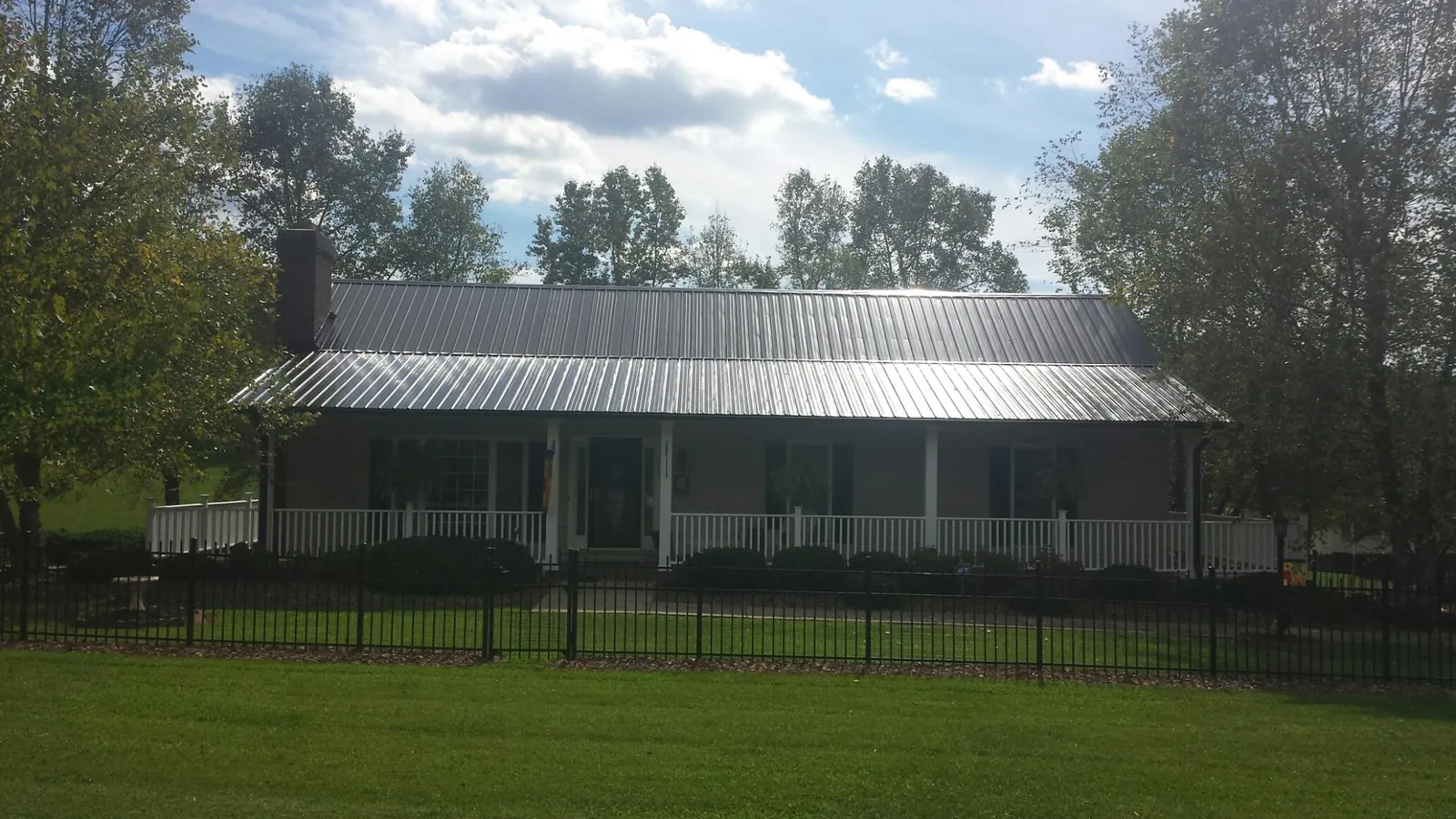 Gray metal roof on a brick ranch with a full width front porch — Gutter Guard Installation work by our crew in Hershey
