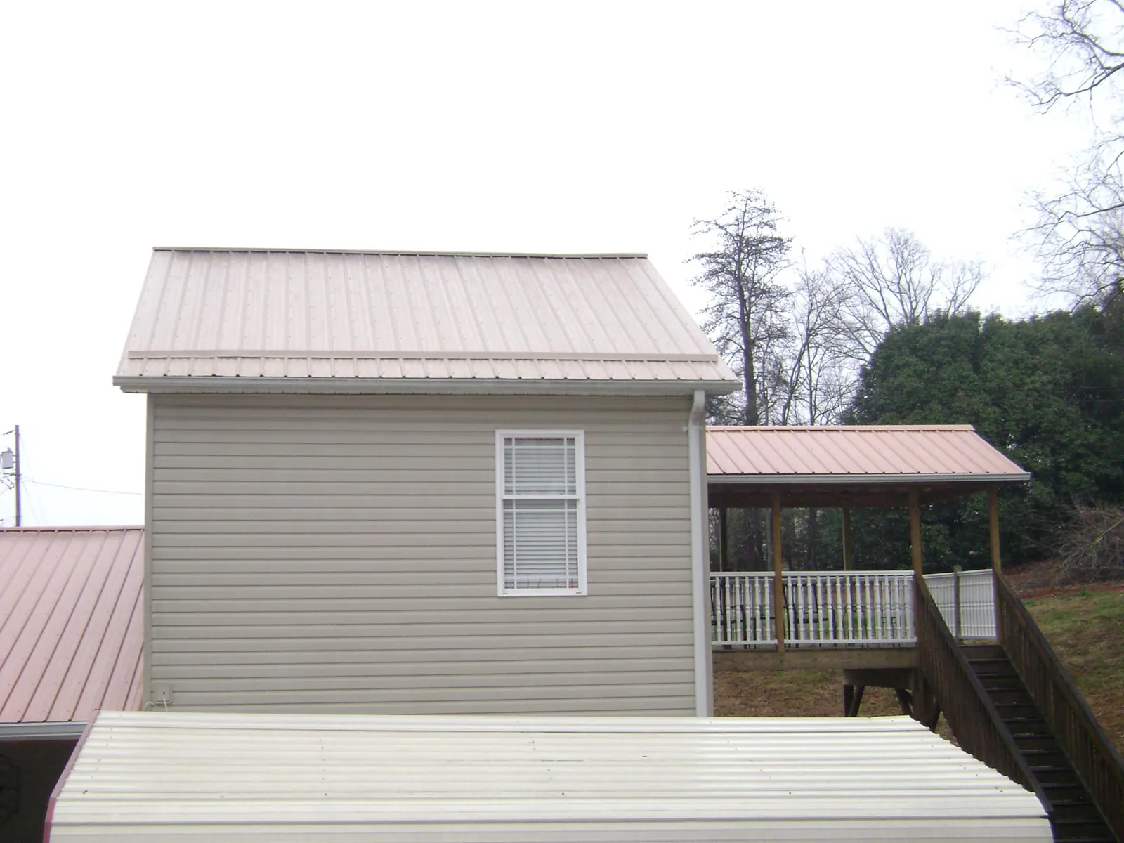 Tan metal roofs on a two story addition and attached porch, from a Roof Replacement job in Hershey