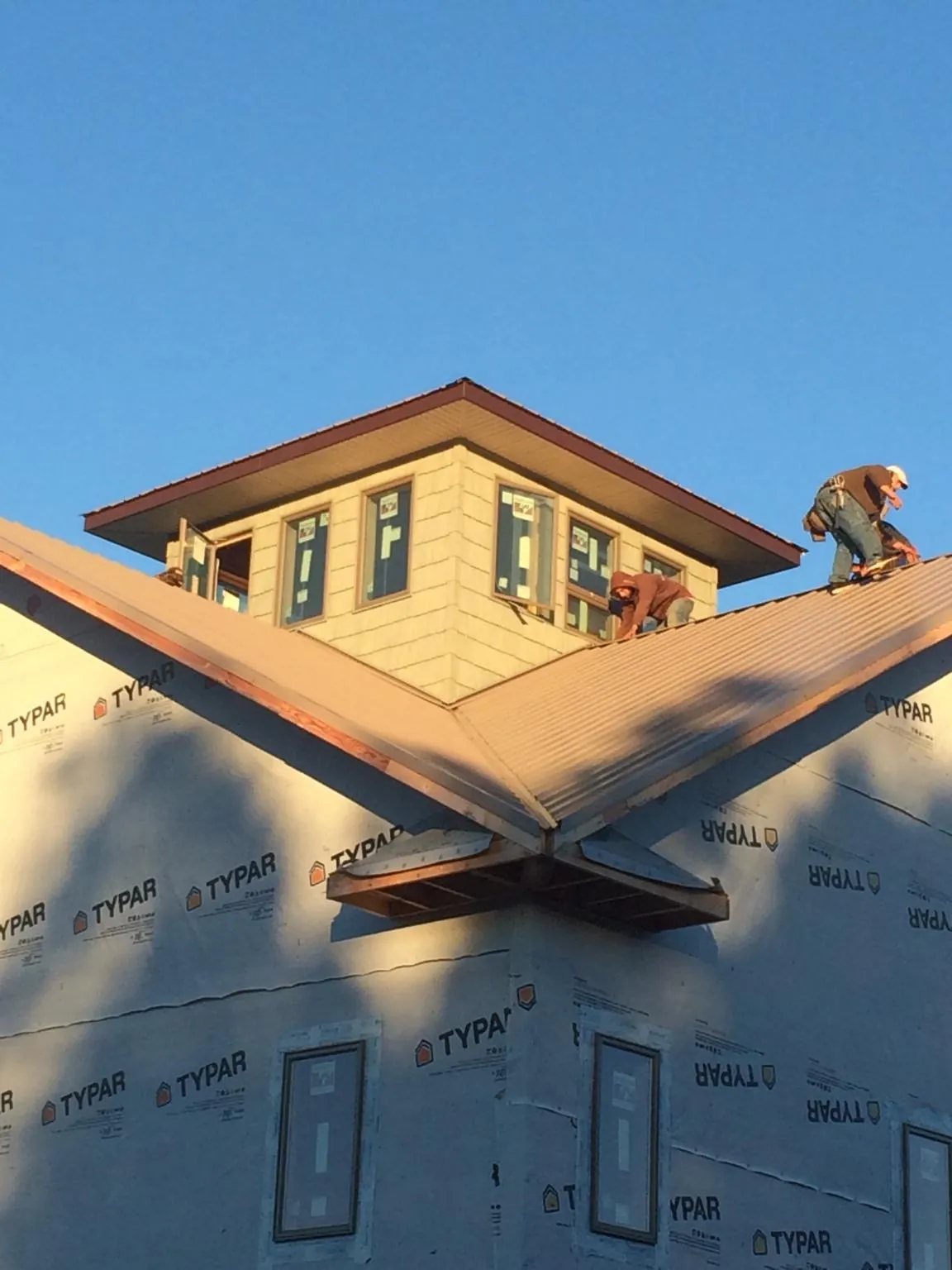 Roofers working around a rooftop cupola on a new metal roof at sunset — Roof Waterproofing in Hershey by Roofing Brothers